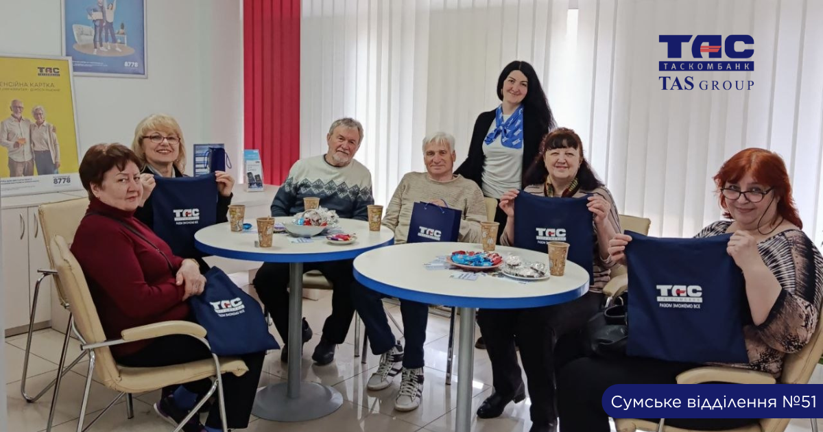 Працівники банку проводять зустріч із клієнтами пенсійного віку, пояснюючи фінансові послуги та правила безпеки для користування банківськими сервісами.